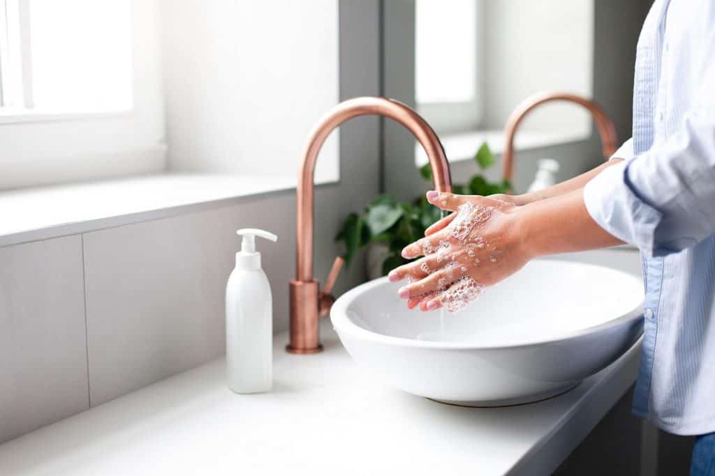 Woman washing hands under tap water